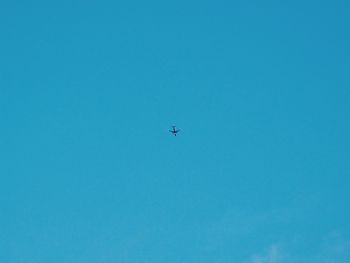 Low angle view of airplane flying against clear blue sky