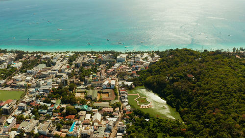 Tropical white beach with tourists and hotels near the blue sea, aerial view. 
