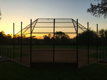 Chainlink fence on field at sunset