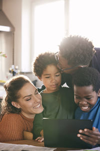 Happy multiracial family enjoying with each other watching digital tablet at home