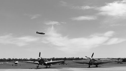 Airplane flying over airport runway against sky