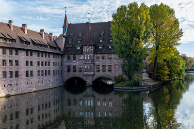 Arch bridge over river by buildings against sky