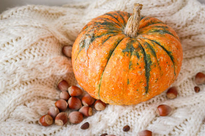 Pumpkin on white knitted sweater. hygge lifestyle, cozy autumn mood. close-up of pumpkin on table