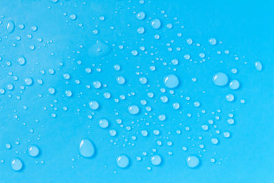 Full frame shot of water drops on blue glass