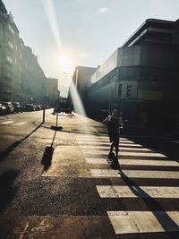 View of city street and buildings against bright sun