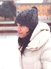 Woman looking away while standing outdoors during winter