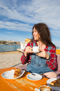 Woman sitting at restaurant table against sky