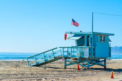 Lifeguard hut on beach against clear blue sky