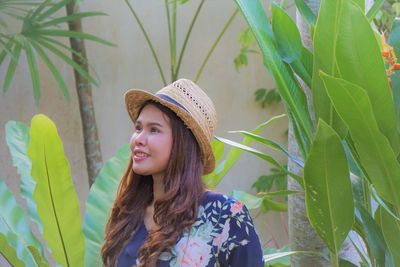 Smiling woman looking away against plants