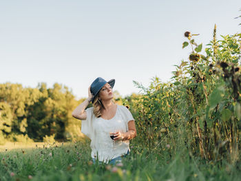 Young millennial woman outdoors at apple orchard enjoying glass of wine in  golden hour sunset