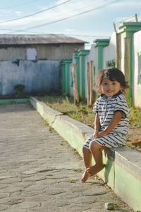 Full length of young woman sitting on footpath