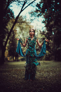 Woman holding umbrella standing against plants