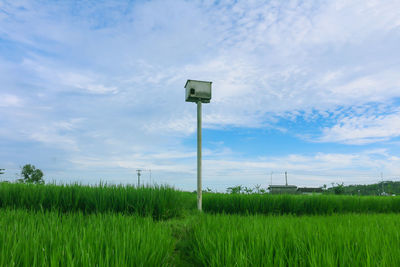 Information sign on field against sky