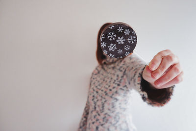 Midsection of woman holding hat against white background