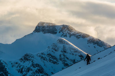 Full length of man standing on snowcapped mountains against sky