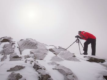 Man standing on snow covered mountain against sky