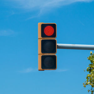 Low angle view of illuminated signal light against blue sky