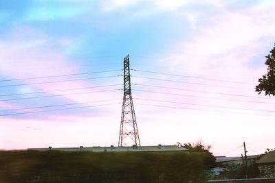 Low angle view of electricity pylon against sky during sunset