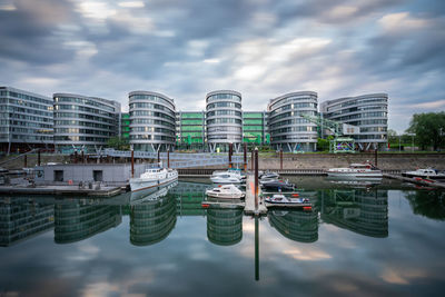 Boats moored in lake against buildings in city