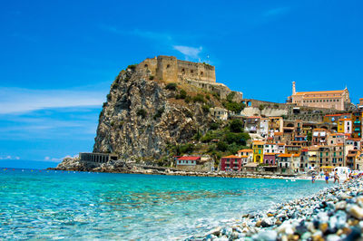 View of sea and buildings against blue sky