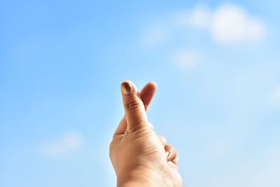 Cropped hand gesturing against sky