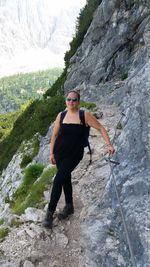 Full length of female hiker standing on rocky mountain