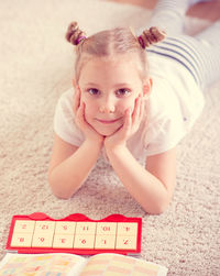 Portrait of girl lying down on carpet at home