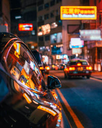 Close-up of car on city street with neon light bokeh