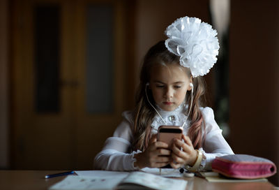 Girl listening to music while using phone at desk in classroom