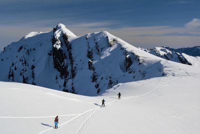 People skiing on snowcapped mountain against sky