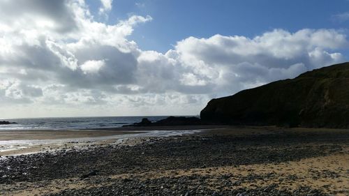 Scenic view of beach against cloudy sky