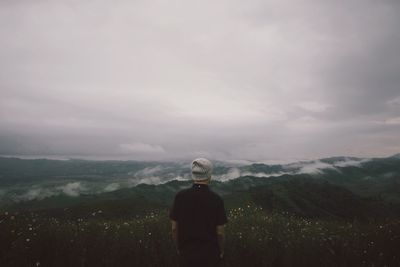 Rear view of woman standing on mountain against sky