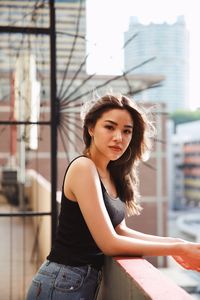 Portrait of young woman standing against building in terrace