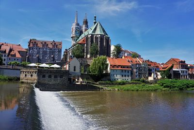 River amidst buildings in city against sky