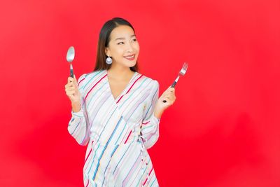 Portrait of a smiling young woman against red background