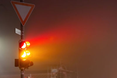 Low angle view of traffic light in foggy night