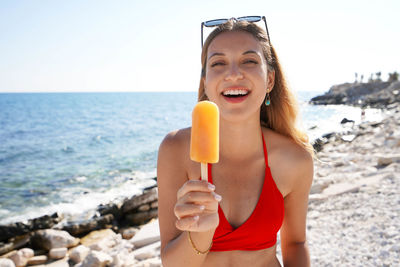 Attractive young brazilian woman holding popsicle looking at the camera on summer