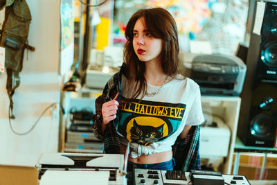 Portrait of young woman standing against wall