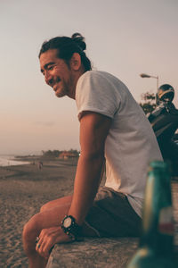 Rear view of man looking at sea shore against sky during sunset