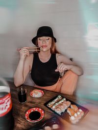 Young woman holding food while sitting on table