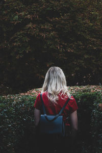Rear view of blonde woman walking into hedges
