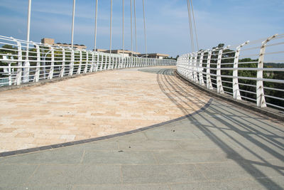 Footpath by bridge against sky in city