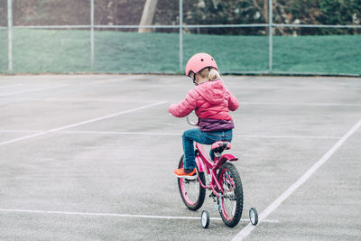 Rear view of girl riding bicycle on walkway