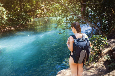 Young woman with backpack standing near rio blanco in costa rica