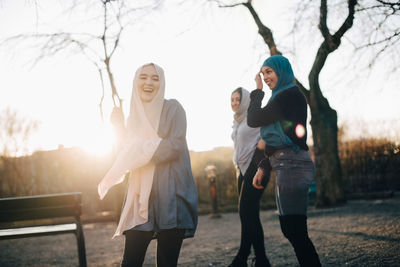Cheerful young muslim female friends standing against clear sky