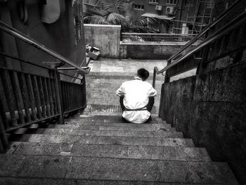 Rear view of man sitting on steps