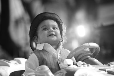 Cute boy sitting in toy car outdoors