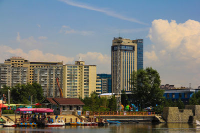 Buildings by river against sky in city