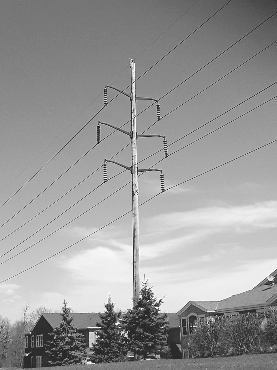 LOW ANGLE VIEW OF ELECTRICITY PYLON AND HOUSES AGAINST SKY