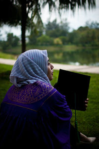 Rear view of woman sitting on field